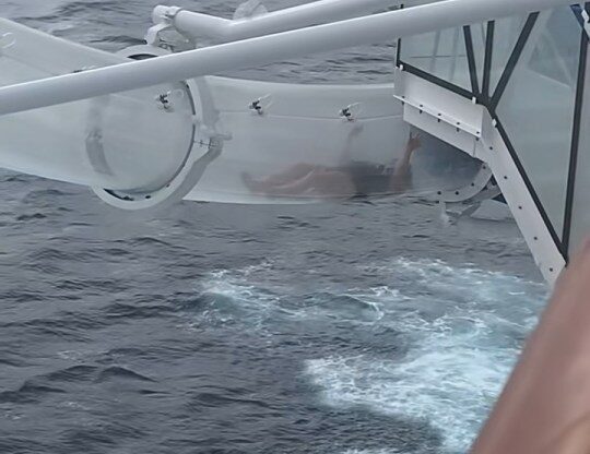Cruise passenger stuck in a clear water slide over the sea.