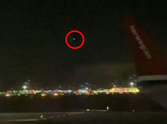 Green light circled in red in the night sky.