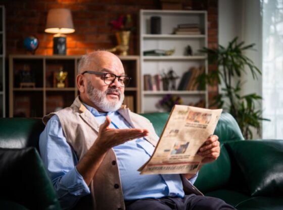 Expresssive Indian asian senior old man reading newspaper at home