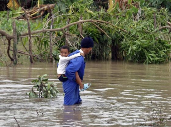 A man crosses a swollen river while carrying a child this Wednesday, in the town of Guama in Santiago de Cuba (Cuba).