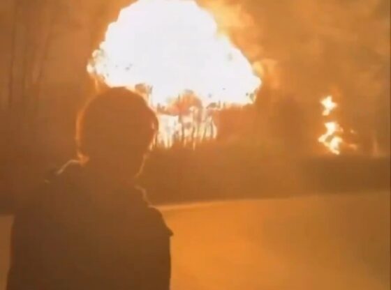 A person watching a large explosion and fire.