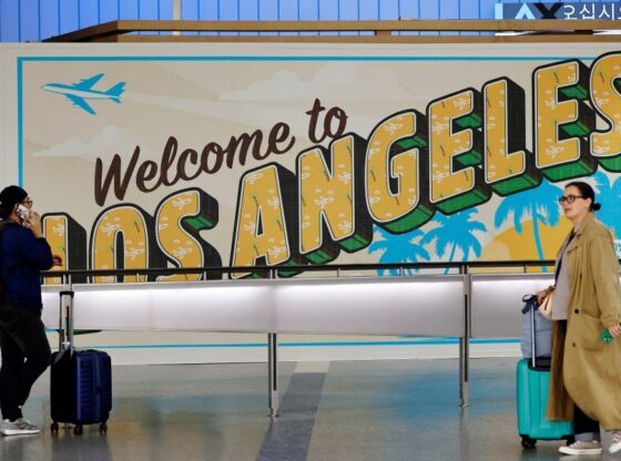 Travelers near a "Welcome to Los Angeles" sign in the international terminal at Los Angeles International Airport.