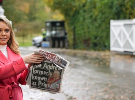 Television presenter holds a newspaper with a photograph of Prince Andrew as she speaks to the camera near the Royal Lodge