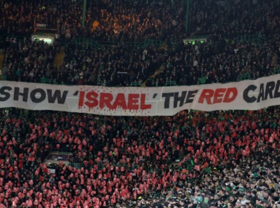 GLASGOW, SCOTLAND - FEBRUARY 12: Fans of Celtic hold up a banner reading SHOW ISRAEL THE RED CARD in solidarity with Palestine during the UEFA Champions League 2024/25 League Knockout Play-off First Leg match between Celtic FC and FC Bayern München at Celtic Park on February 12, 2025 in Glasgow, Scotland. (Photo by Ian MacNicol/Getty Images)