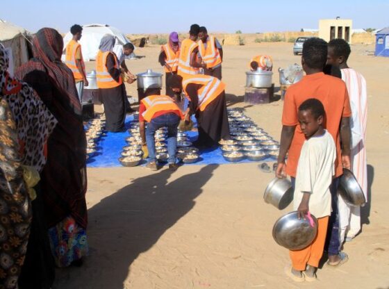 Sudanese who fled El-Fasher queue to receive free meals at the Al-Afad camp for displaced people in the town of Al-Dabba, northern Sudan, on November 20, 2025.