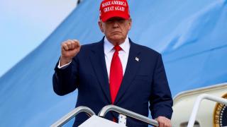 Donald Trump wears the MAGA hat as he gets off Air Force One after his trip to Asia.