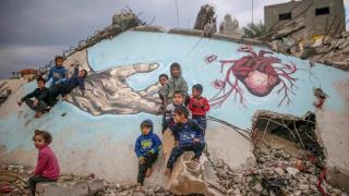 File image of internally displaced Palestinian children playing next to a mural in Deir Al Balah, Gaza.
